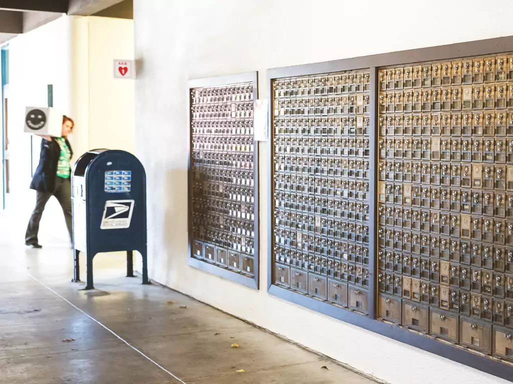 Row of mailboxes with student carrying box into Mail and Copy center