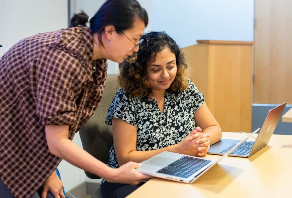 Student and professor review material on laptop