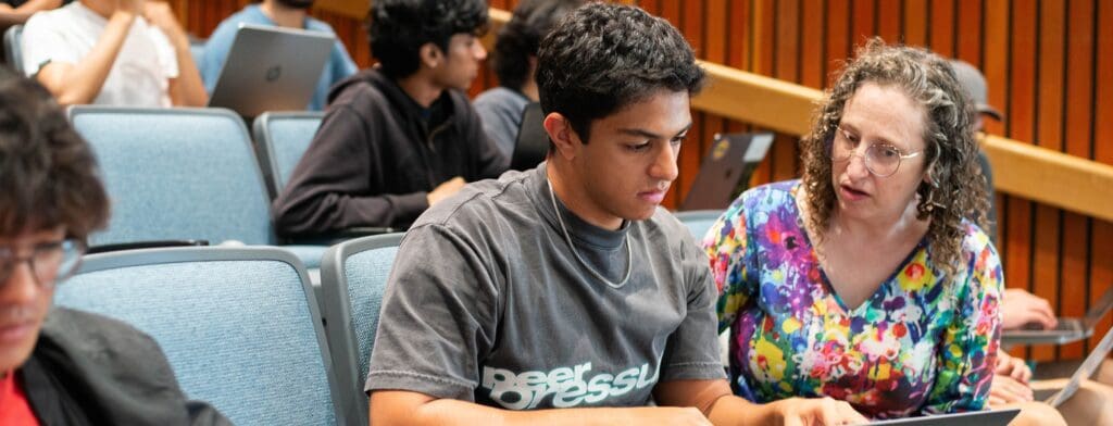 Ellen Spertus sits in lecture hall with student discusses what is shown on their laptop