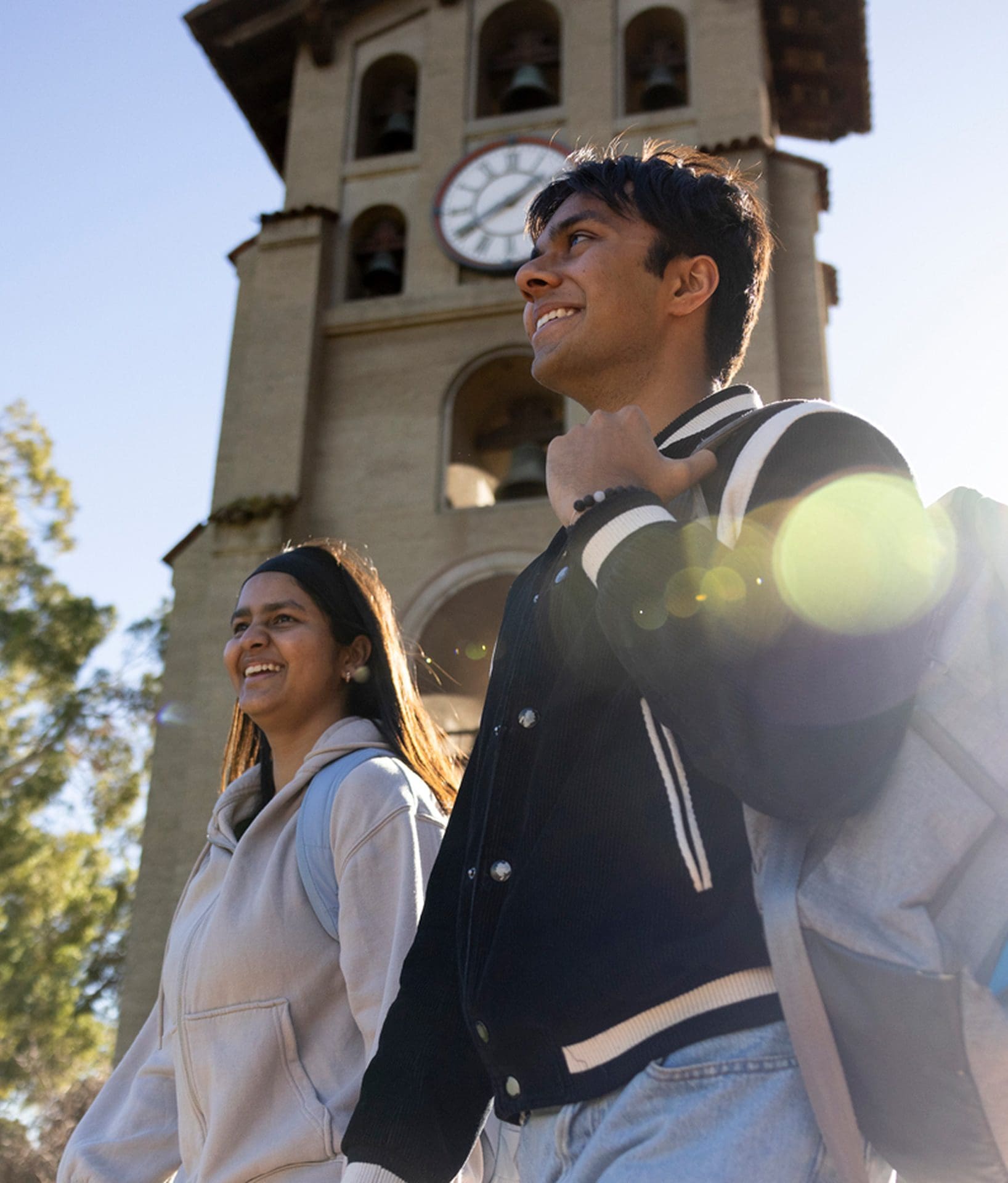 Two students walk past Julia Morgan's Campanil clock tower on Northeastern University's Oakland campus