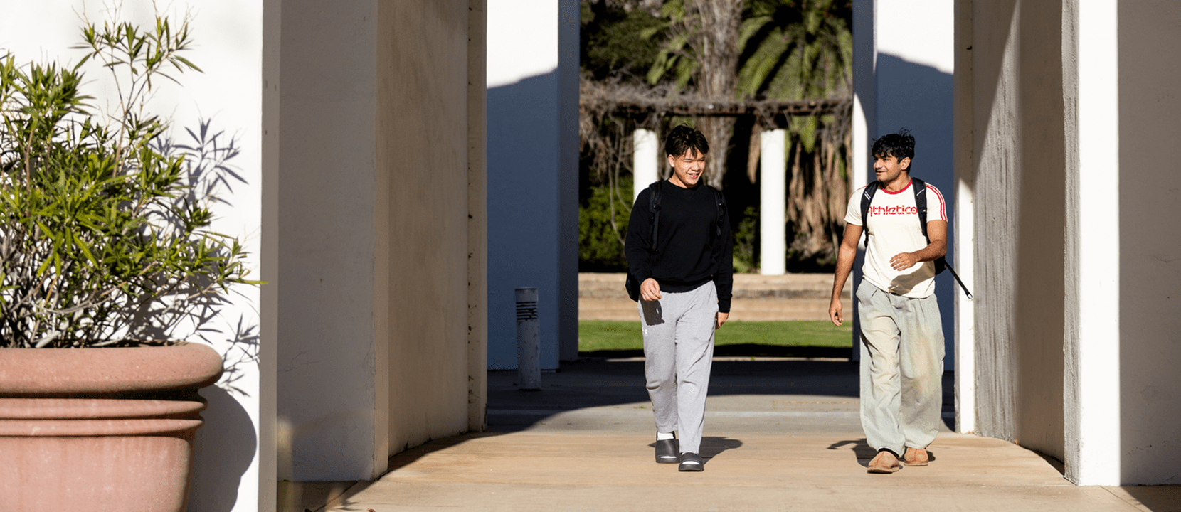 Two young men walk between arches of the Aaron Art Center.