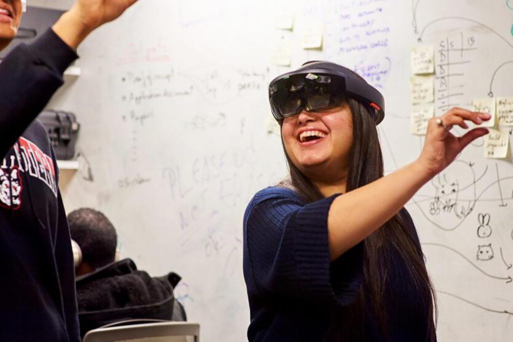 Two students wearing VR goggles interact with virtual object